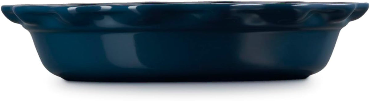 Side view of a dark blue glazed ceramic baking dish with a fluted rim, shown from a side angle on a white background.