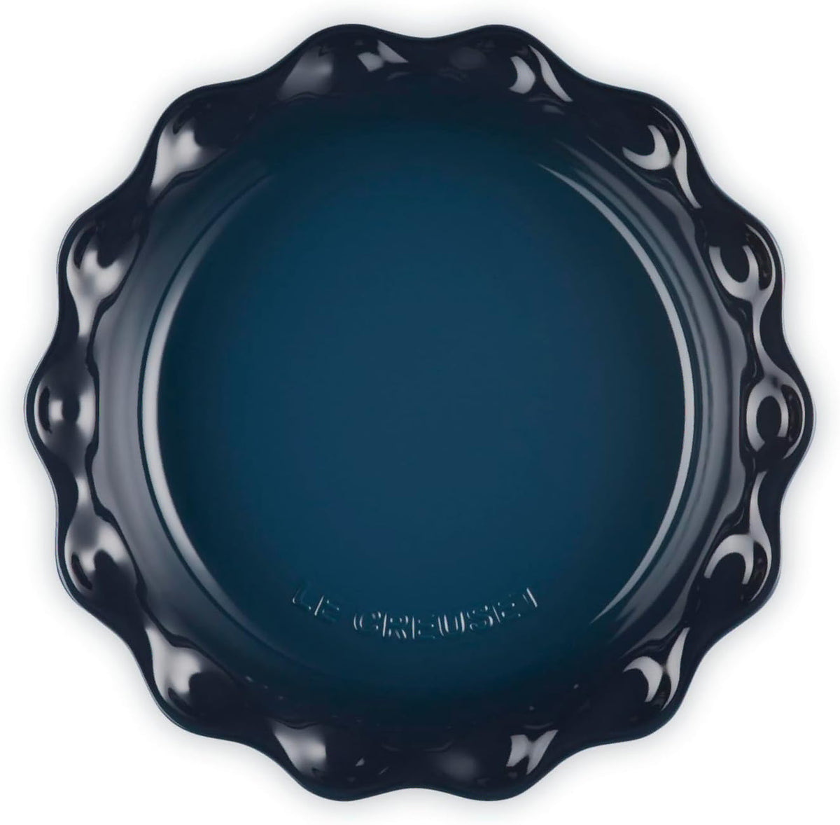 Top view of a dark navy blue ceramic baking dish with a decorative wavy rim, photographed from directly above on a white background.