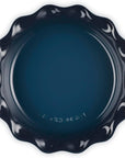 Top view of a dark navy blue ceramic baking dish with a decorative wavy rim, photographed from directly above on a white background.