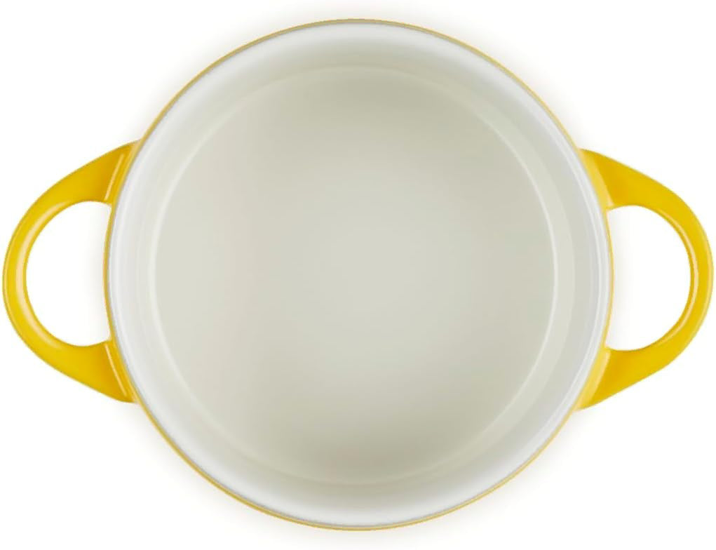 A top-down view of a round white ceramic pot with bright yellow handles and a thin yellow rim, set against a plain white background.