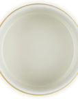 A top-down view of a round white ceramic pot with bright yellow handles and a thin yellow rim, set against a plain white background.