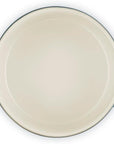 An oval-shaped enameled cast iron Dutch oven shown from a top-down perspective, featuring a cream-colored interior and dark navy blue handles.