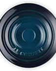 Top-down view of a Le Creuset round lidded casserole dish in a dark teal enamel finish, featuring two side handles and the embossed Le Creuset brand name on the bottom of the lid.