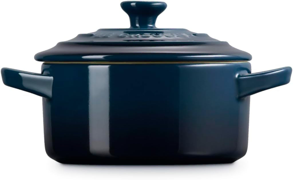Side view of a dark blue enameled cast iron pot with a matching lid, featuring side handles and a glossy finish, shown on a white background.