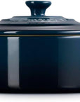 Side view of a dark blue enameled cast iron pot with a matching lid, featuring side handles and a glossy finish, shown on a white background.