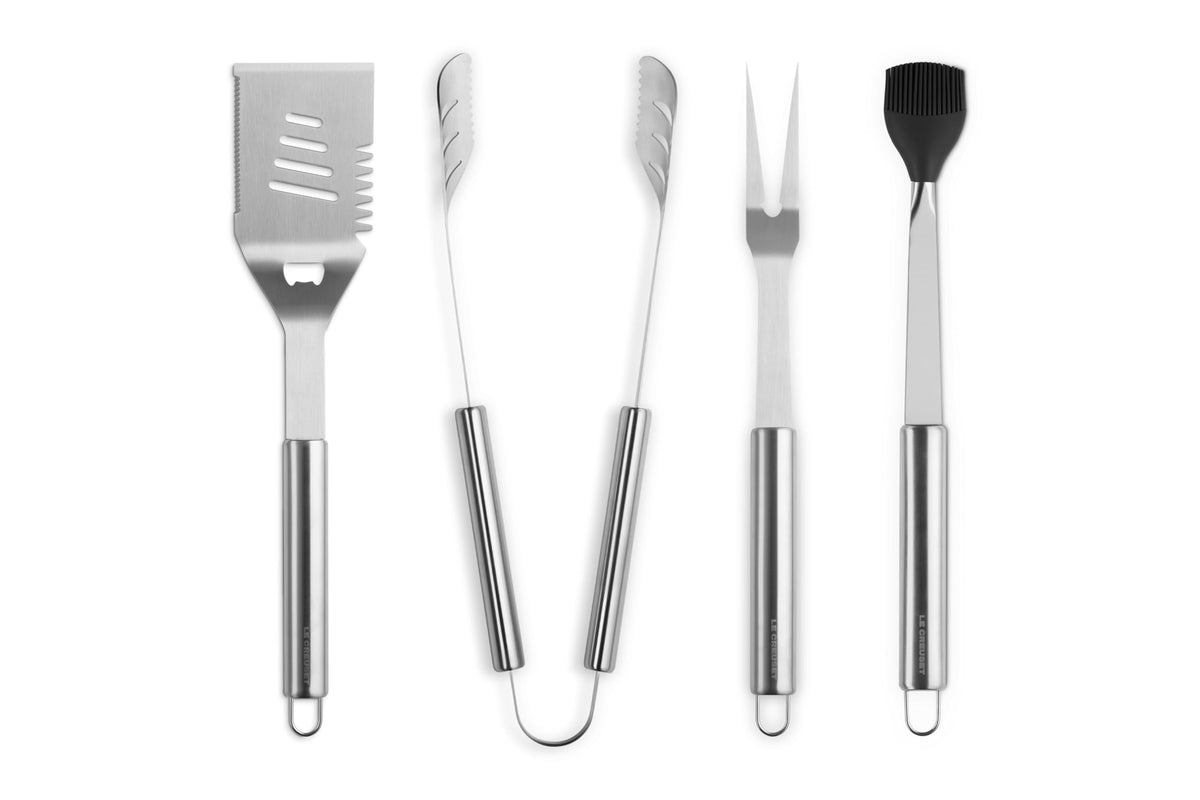 Set of five stainless steel barbecue tools on a white background