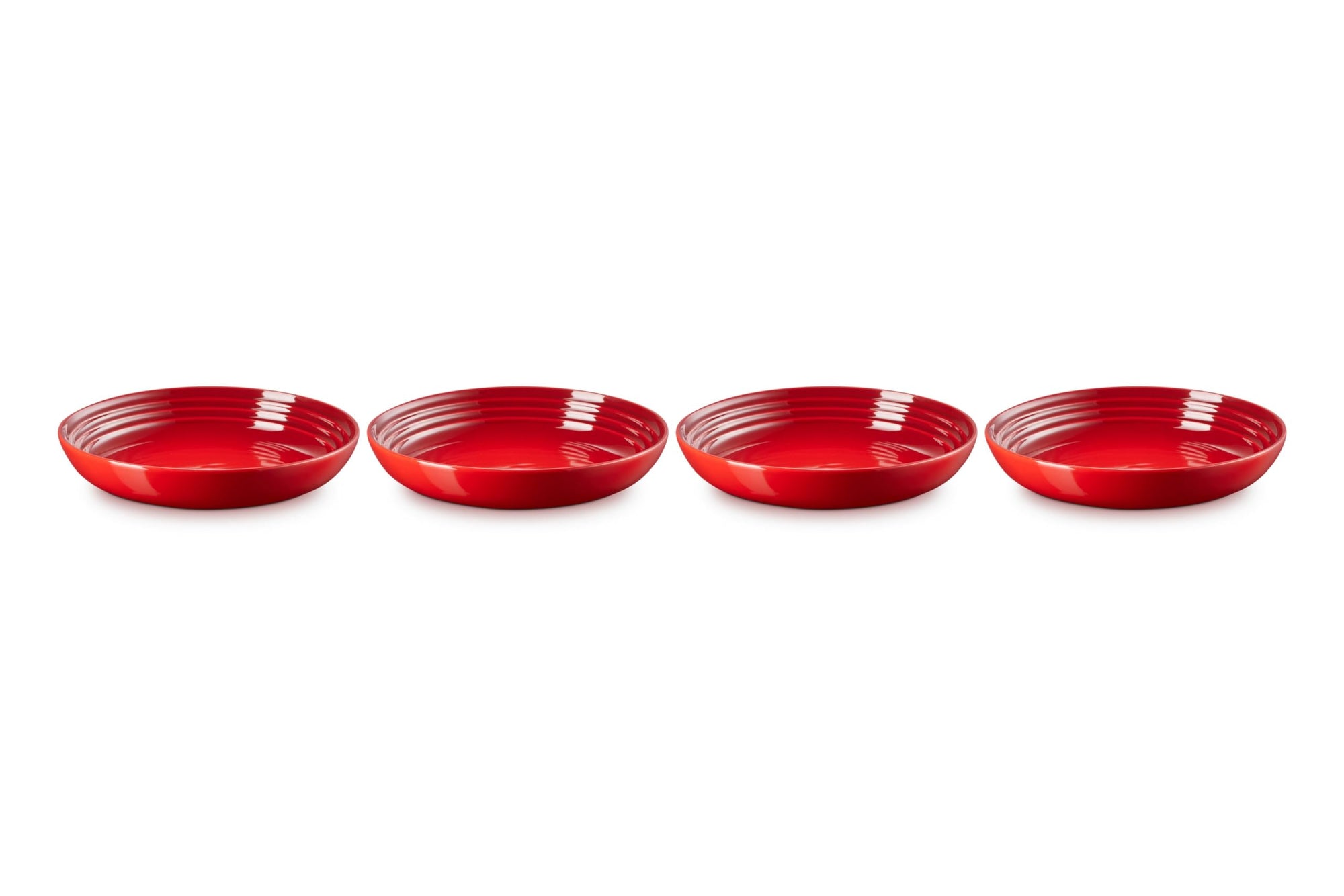 Four red ceramic bowls lined up on a white background
