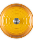 Top-down view of a Le Creuset round enameled cast iron pot in a vibrant yellow-orange color, featuring two side handles and a silver metal knob in the center, set against a plain white background.
