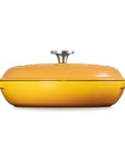 A yellow enameled cast iron Dutch oven with a matching lid and side handles, featuring a silver metal knob on top, shown against a plain white background.