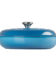 A blue enameled cast iron Dutch oven with a matching lid and side handles, shown from a side view on a solid white background.