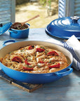 Blue cast iron skillet with baked dish on a wooden table
