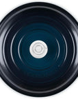 Top-down view of a Le Creuset round enameled cast iron pot or Dutch oven with side handles, showing a dark navy blue interior and a silver metal center insert.