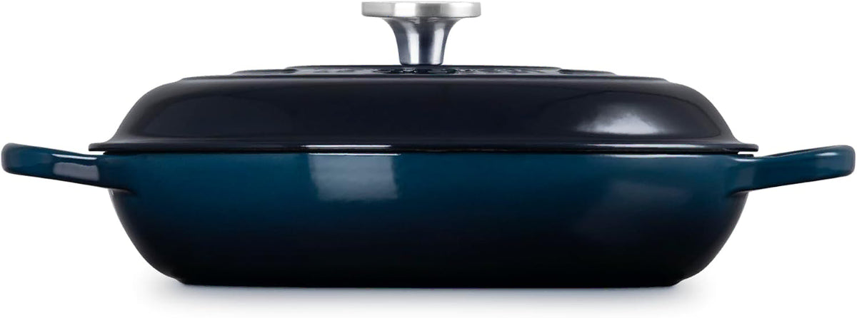 Side view of a dark navy blue enameled cast iron Dutch oven with a matching lid and side handles, featuring a silver knob on top, shown against a plain white background.