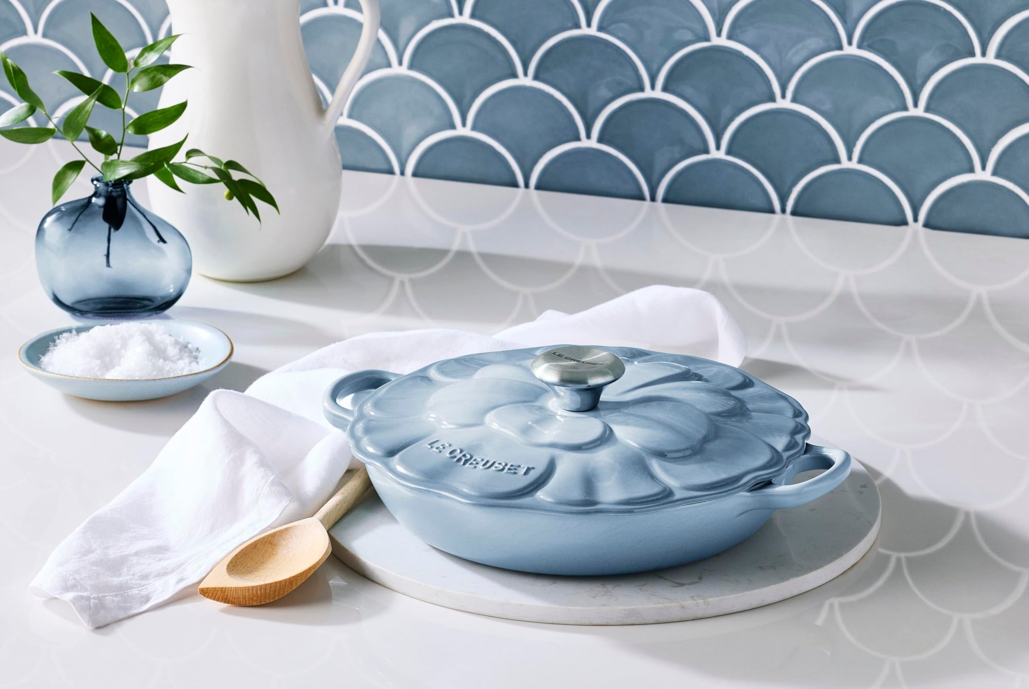 Blue ceramic pot with lid on a kitchen counter, surrounded by decorative items.