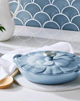Blue ceramic pot with lid on a kitchen counter, surrounded by decorative items.