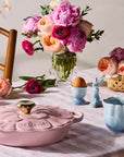 Pastel-colored tableware on a checkered tablecloth with flowers and eggs.