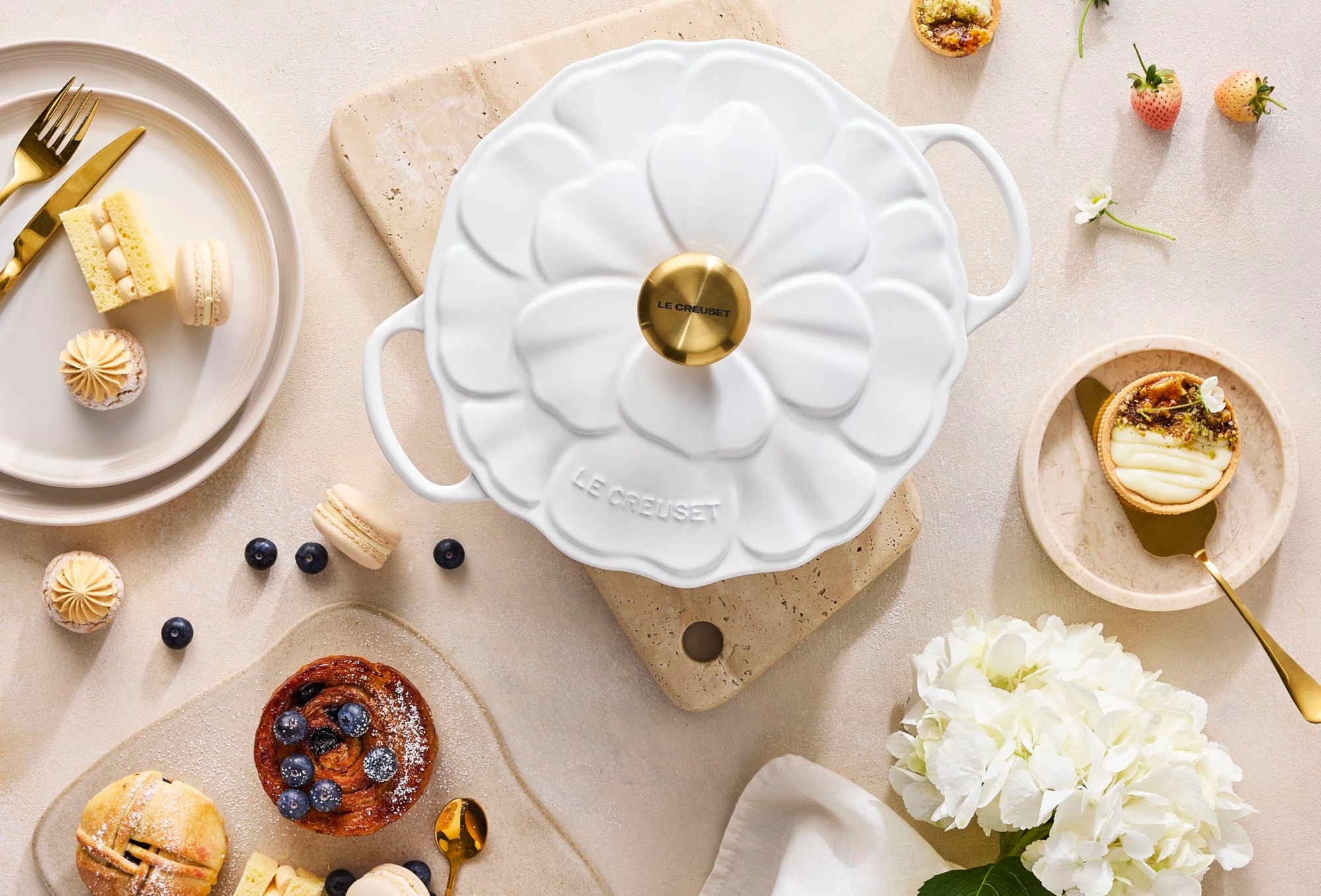 White ceramic mold with gold accents on a table with pastries and flowers