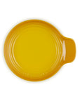 A round yellow ceramic spoon rest with a small side handle, photographed from directly above on a white background.