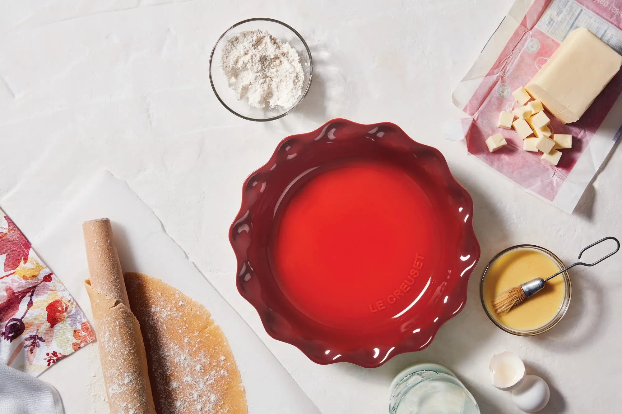 Top view of cerise Heritage 9" Pie Dish next to baking materials on a water countertop