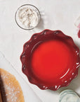Top view of cerise Heritage 9" Pie Dish next to baking materials on a water countertop