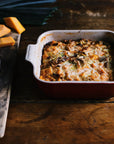 Cerise Heritage 3 Qt Square Dish with a casserole inside displayed on a wooden surface next to eggs and cheese