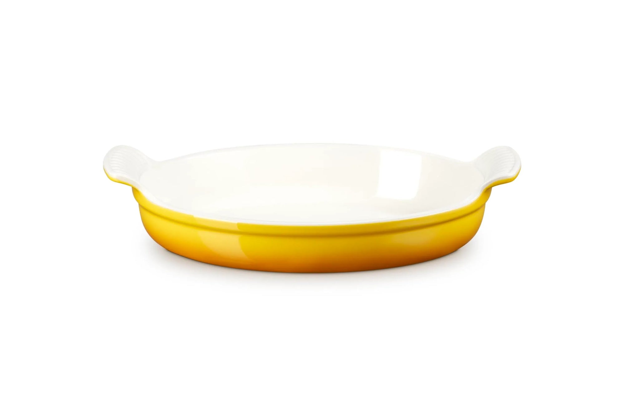 An oval ceramic baking dish with a glossy white interior and a vibrant yellow exterior, featuring small side handles on a clean white background.