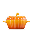 Side view of a persimmon cast-iron pumpkin-shaped lidded cocotte with side handles, shown on a plain white background.