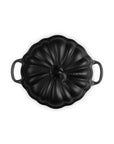 A black enameled cast iron Dutch oven lid with a ribbed pumpkin-like design and side handles, shown from a top-down view on a white background.