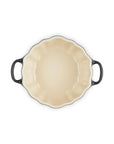 An oval baking dish with a cream-colored interior and dark gray handles, shown from a top-down view on a white background.