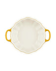A white ceramic baking dish with a scalloped rim, two yellow handles, and a yellow-gold rim, shown from a top-down view on a white background.