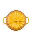 A yellow enameled cast iron Dutch oven with a pumpkin-shaped design and two side handles, shown from a top-down view on a white background.