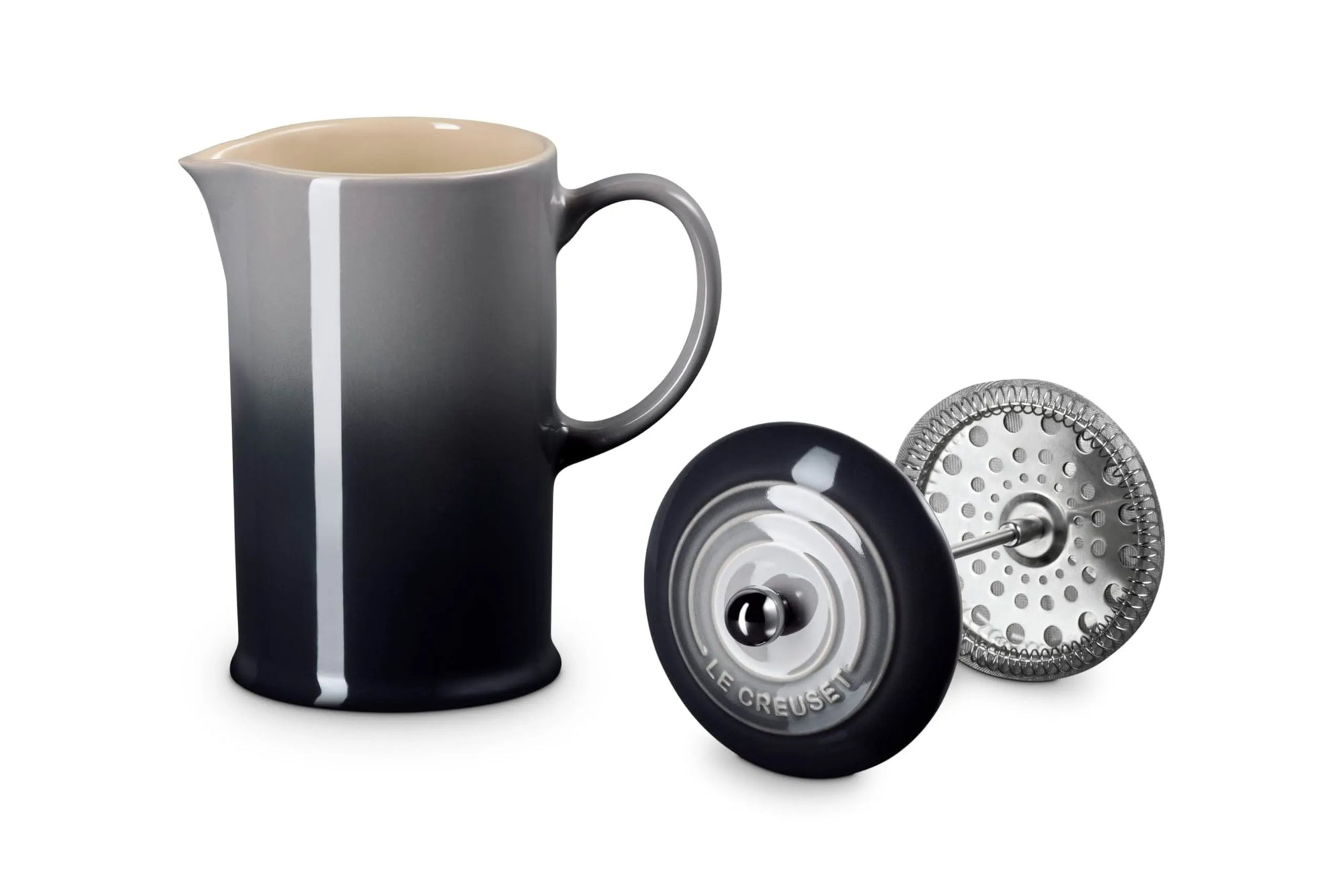 A ceramic French press pitcher with a black-to-gray gradient finish, shown alongside its black lid and metal infuser filter on a white background.