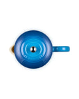 Top-down view of a Le Creuset enameled French press in a vibrant blue color, showing the lid, spout, and handle against a solid white background.