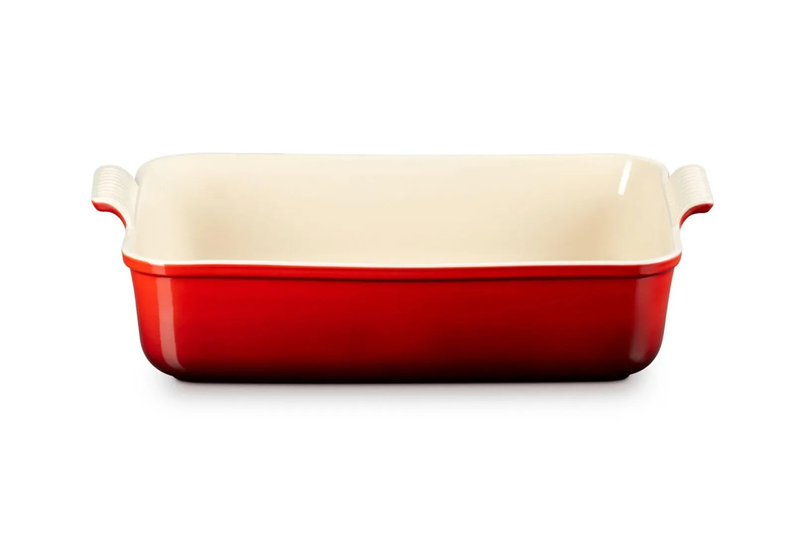 A rectangular ceramic baking dish with a glossy red exterior and a cream-colored interior, featuring integrated side handles, shown on a plain white background.