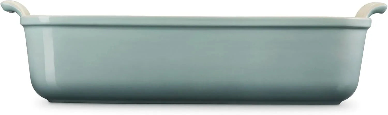 Side view of a rectangular ceramic baking dish in a muted sage green color, featuring two small white handles on the sides, shown against a plain white background.