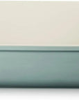 A rectangular ceramic baking dish with side handles, featuring a pale mint green exterior and a warm cream-colored interior, shown against a plain white background.