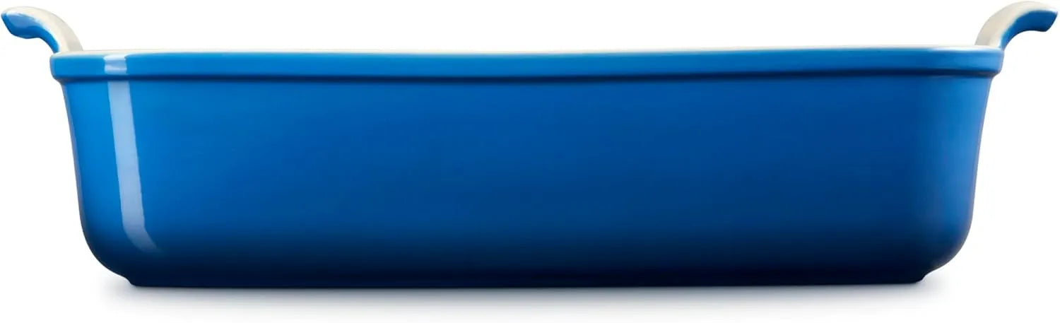 Side view of a blue rectangular baking casserole dish with two small loop handles on the sides, shown from a front-facing perspective on a solid white background.