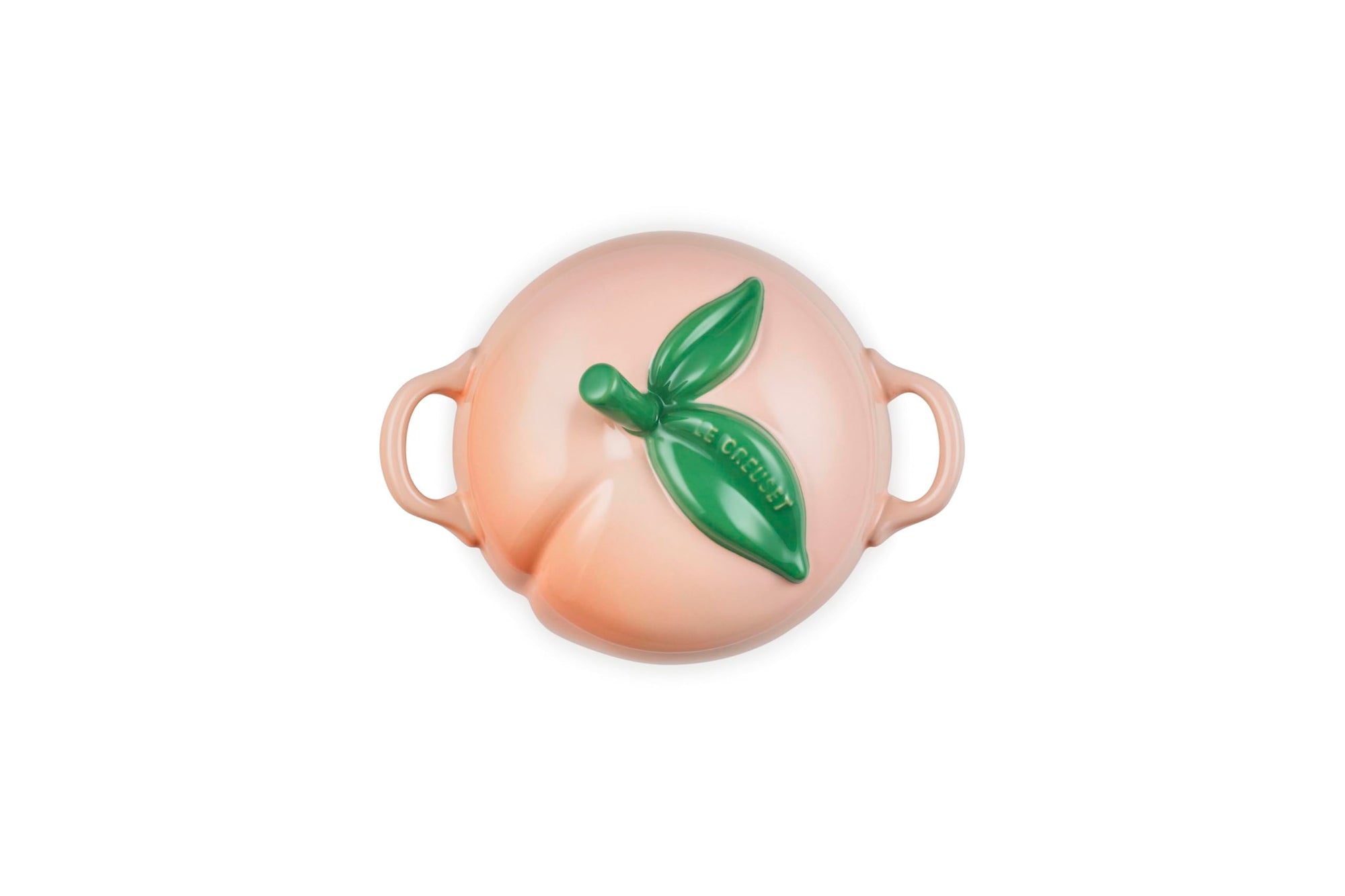 Top view of Peach-shaped ceramic container with a green leaf on a white background