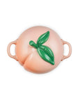 Top view of Peach-shaped ceramic container with a green leaf on a white background