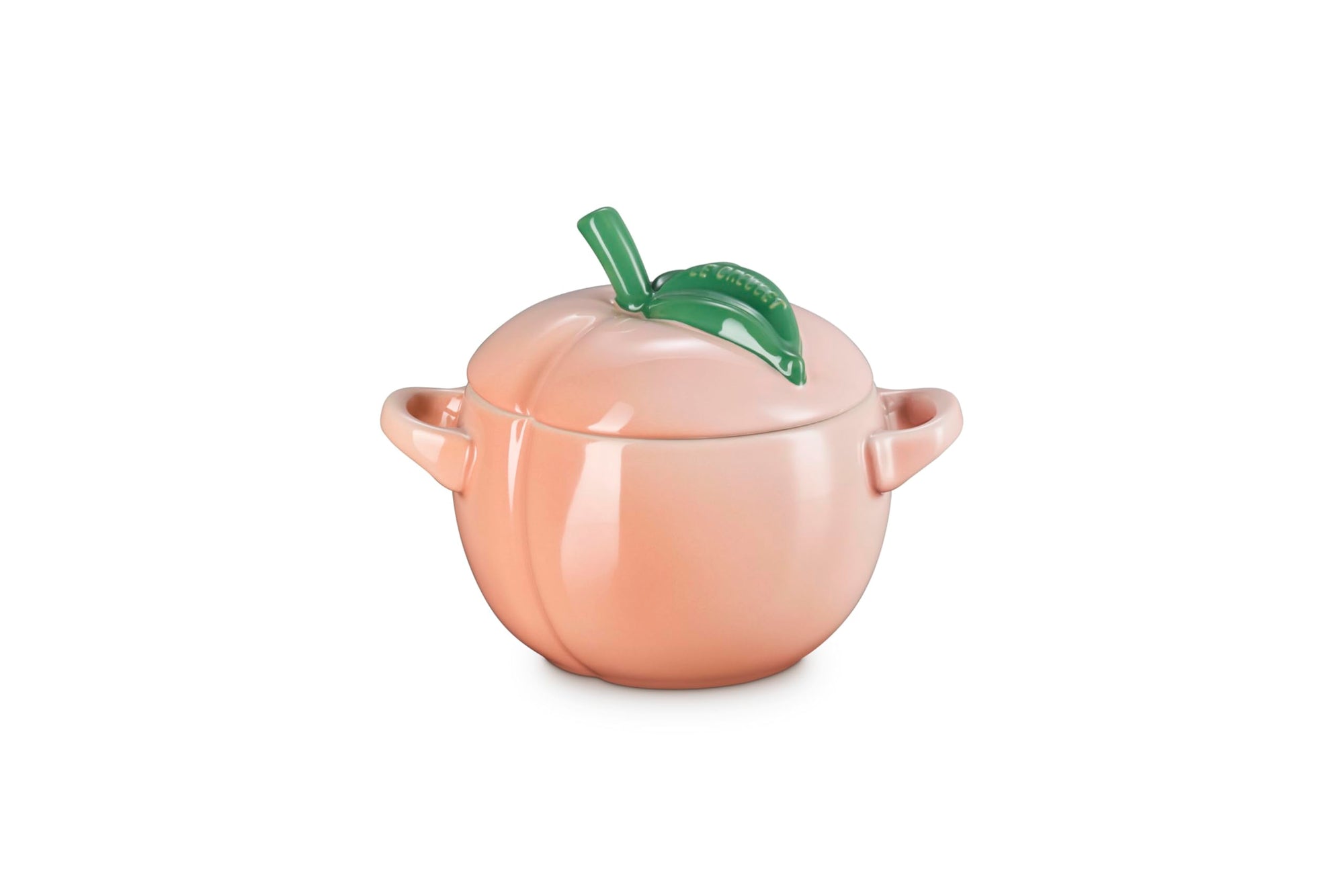 Side view of Peach-shaped ceramic container with a green leaf on a white background