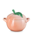 Side view of Peach-shaped ceramic container with a green leaf on a white background