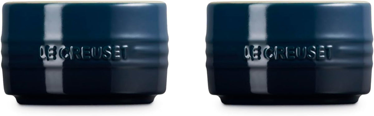 Side view of two dark navy blue Le Creuset lidded ceramic jars shown side by side on a white background.