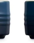 Side view of two dark navy blue Le Creuset lidded ceramic jars shown side by side on a white background.