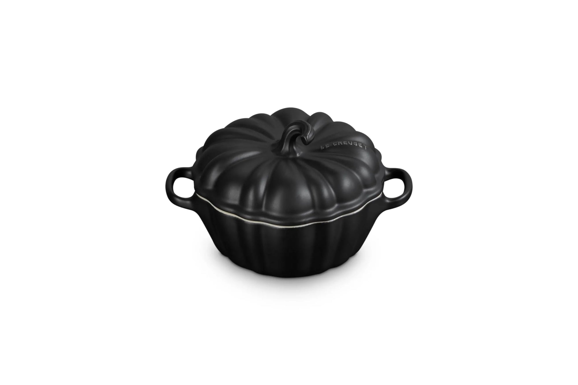 A black cast iron pumpkin-shaped lidded cocotte dish with side handles, shown on a solid white background.