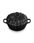 A black cast iron pumpkin-shaped lidded cocotte dish with side handles, shown on a solid white background.