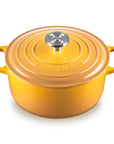 A yellow-orange enameled cast iron Dutch oven with a matching lid and side handles, featuring a silver knob, on a white background.