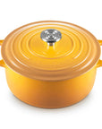 A Le Creuset enameled cast iron Dutch oven in a vibrant yellow-orange color, featuring a matching lid with a silver stainless steel knob, set against a plain white background.