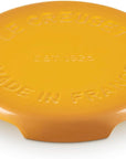 A yellow Le Creuset round trivet with embossed text reading 'LE CREUSET', 'EST. 1925', and 'MADE IN FRANCE' on a white background.