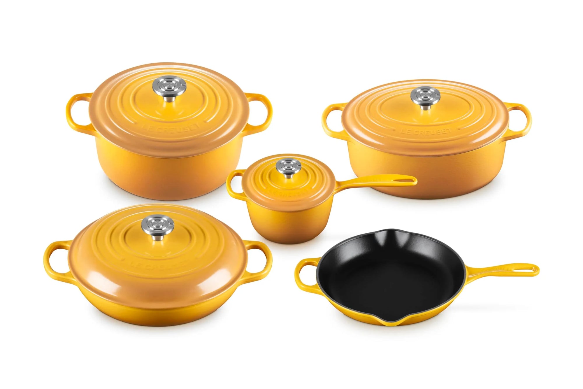 A 5-piece enameled cast iron cookware set in a vibrant yellow-orange color, including three pots of varying sizes with lids, a small saucepan with lid, and a black skillet, arranged on a clean white background.