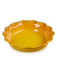 A small yellow ceramic pie dish with a scalloped rim, shown on a plain white background.